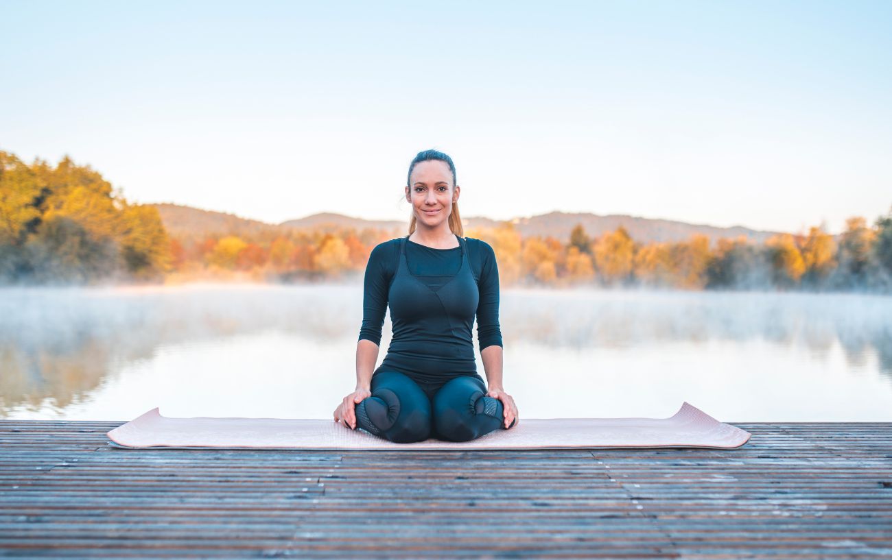 woman in hero pose by a lake