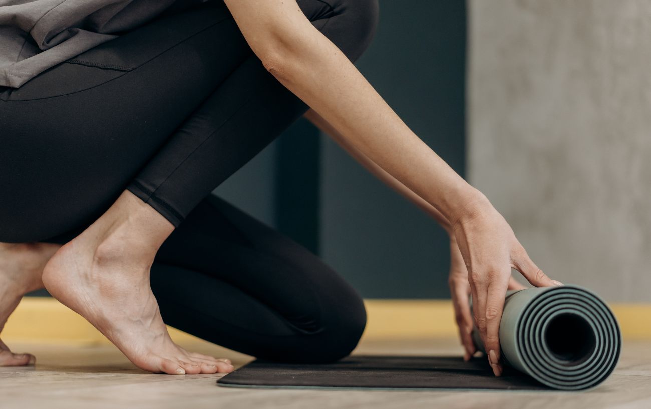 person rolling out a yoga mat