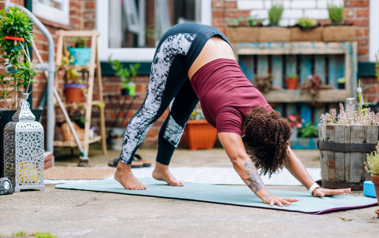 a woman doing downward dog yoga pose in her garden