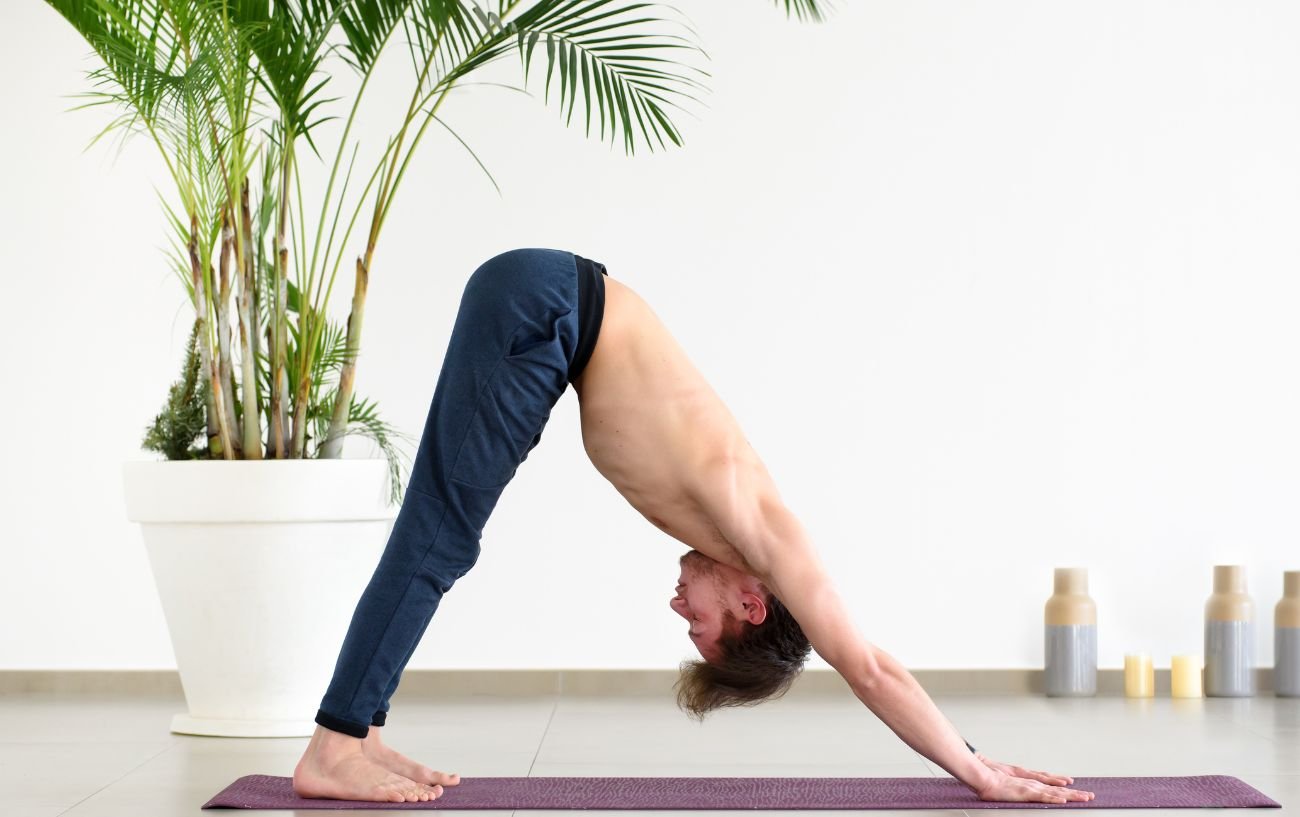 a man doing downward dog on a yoga mat