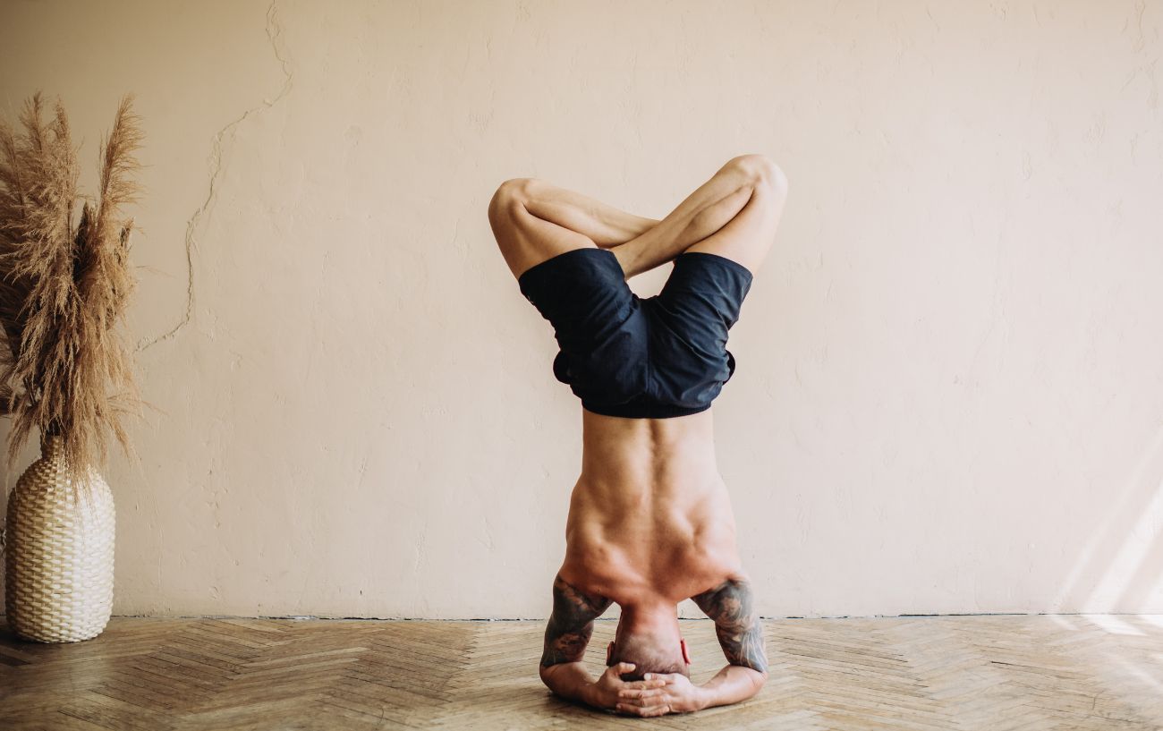 a man doing a tripod headstand with crossed legs