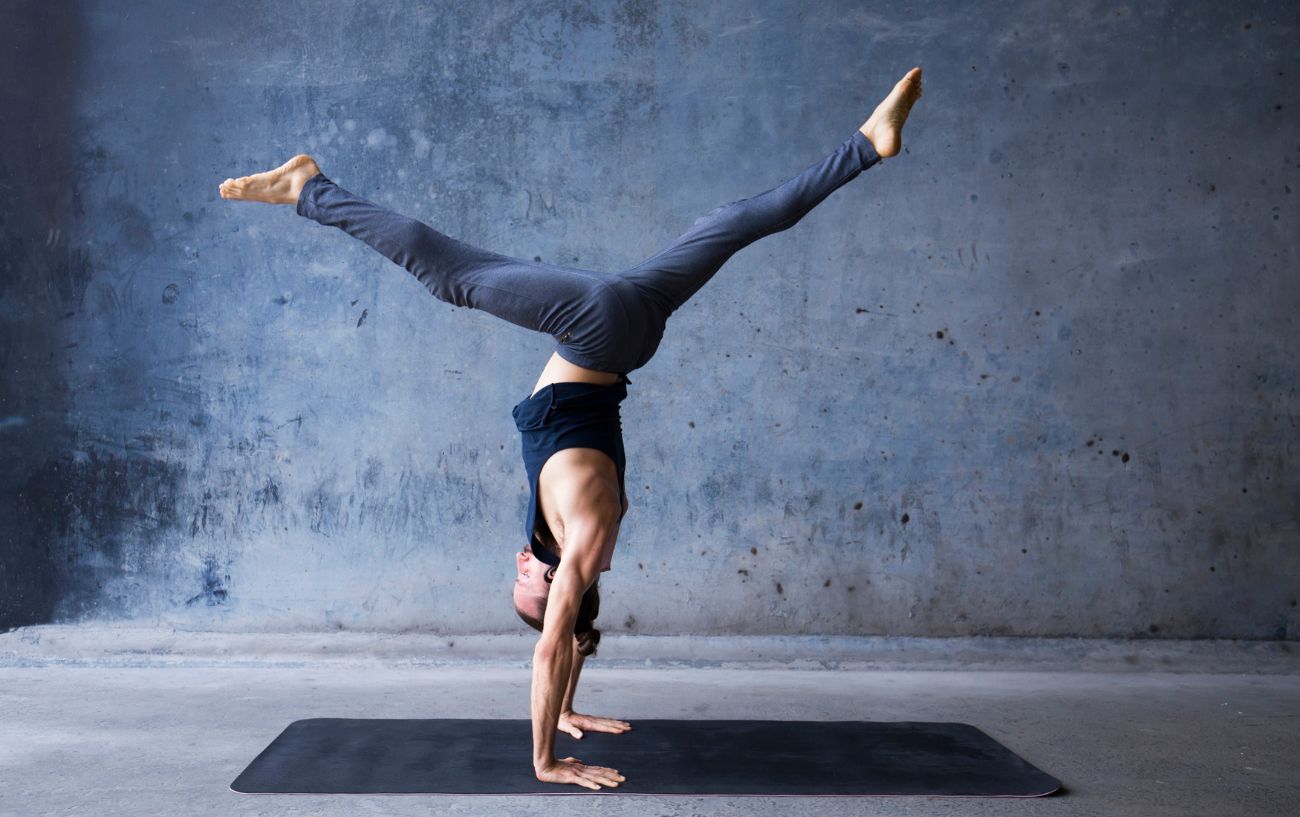 a man doing a handstand in a grey room