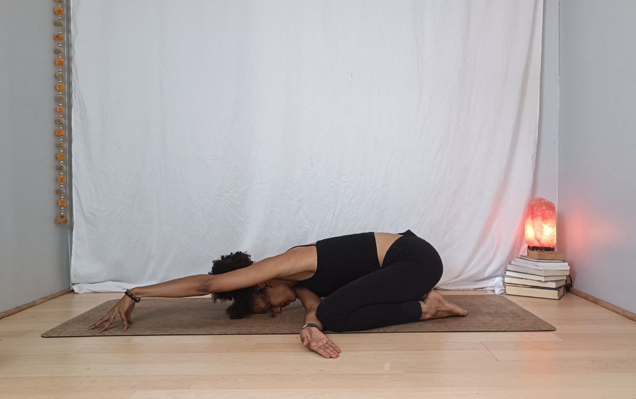 a woman doing a thread the needle child's pose variation on a yoga mat