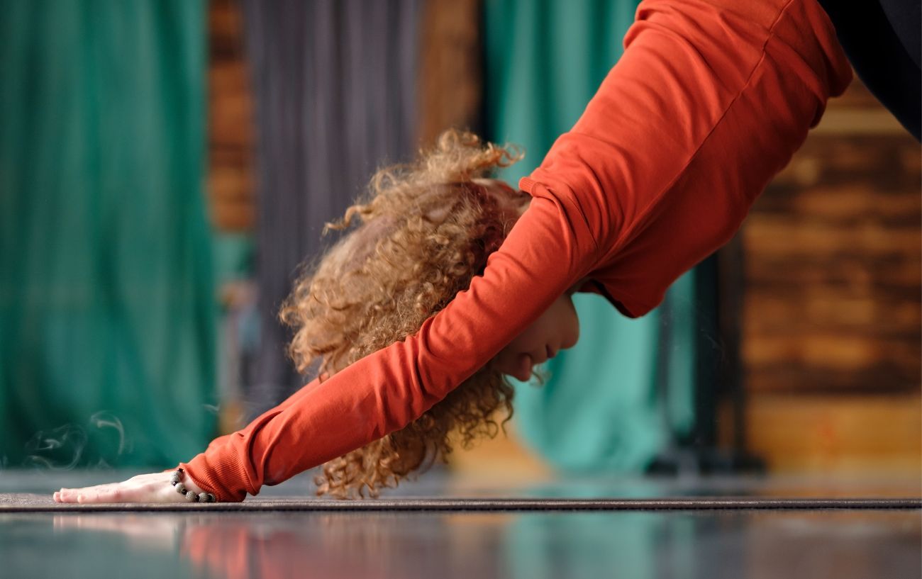 a woman in a red top doing downward dog, a yoga pose