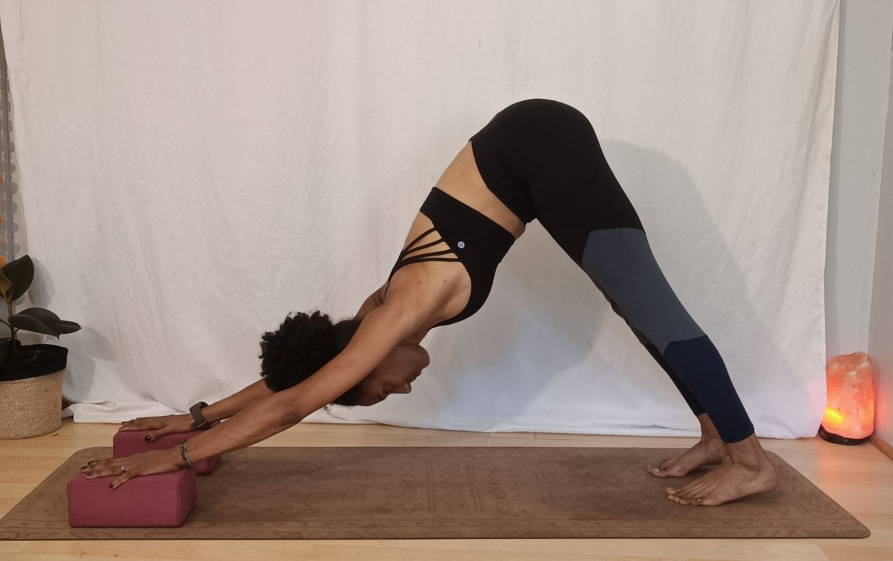 a woman doing downward facing dog with hands on blocks