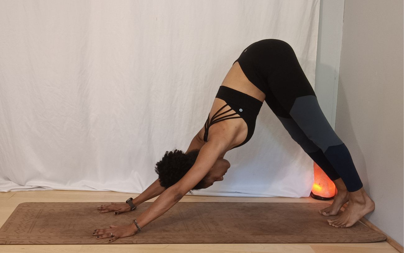 a woman doing downward facing dog with heels against a wall