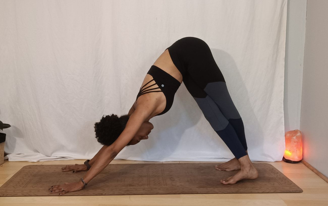 a woman doing downward facing dog with her legs crossed