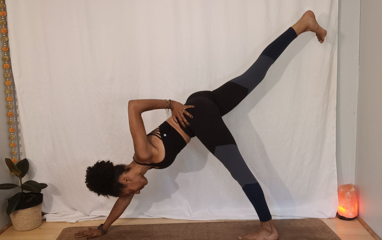 a woman doing a pne legged and one handed downward facing dog