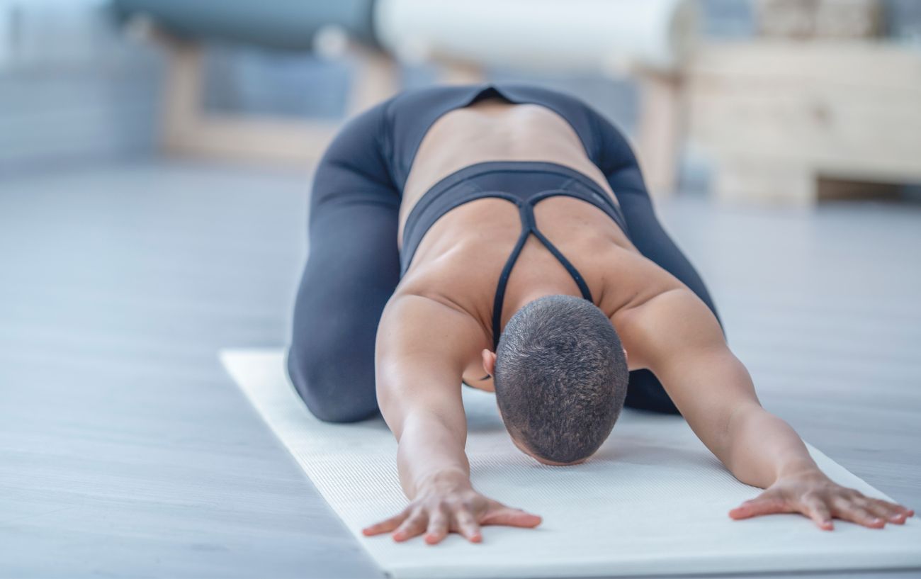 a woman practicing child's pose in yoga clothes