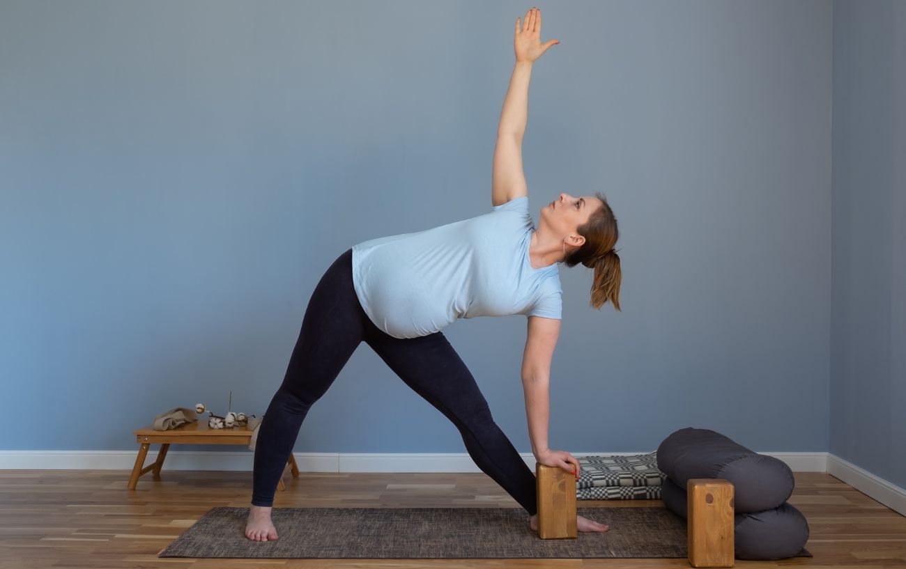 a pregnant woman doing triangle pose on a yoga mat