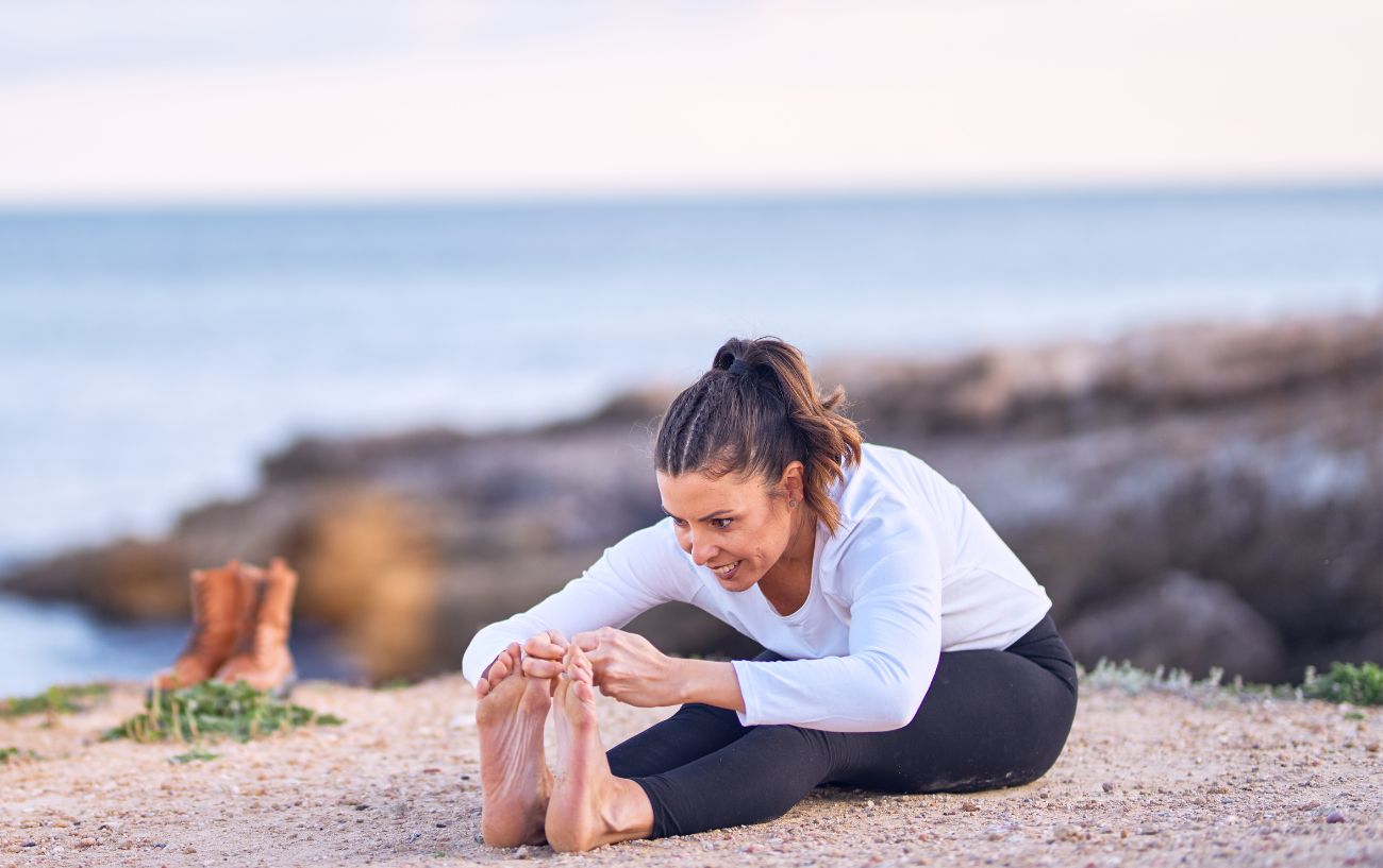 a woman doing a forward fold on a cliff