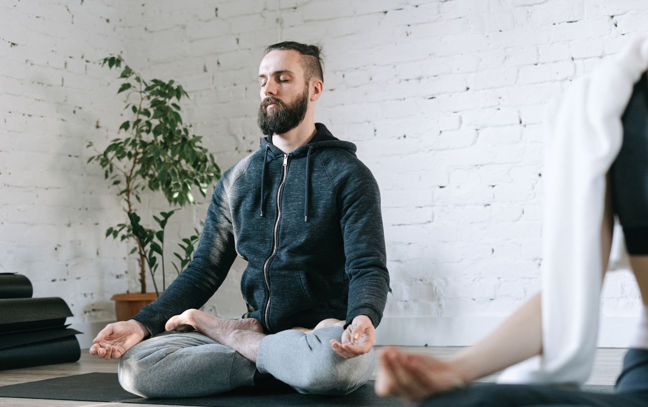 man sat in easy pose on yoga mat