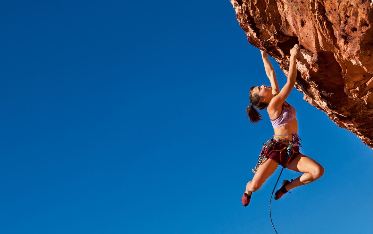 woman climbing on the side of a cliff