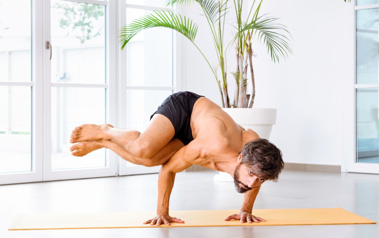 man doing side crow pose