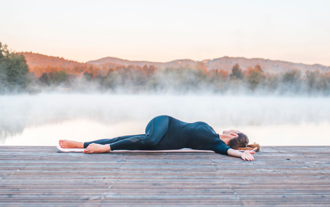 woman by a lake in a supine twist