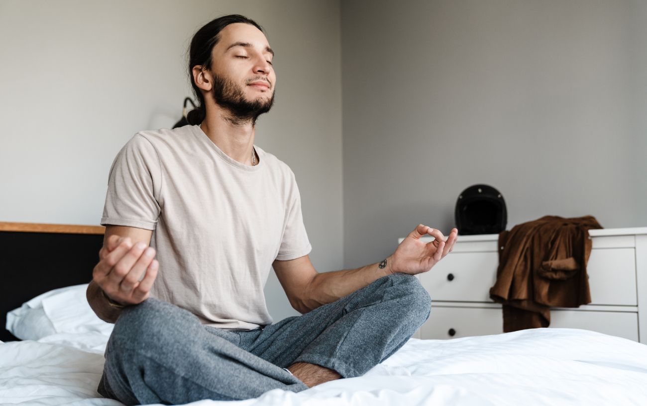 man meditating on his bed