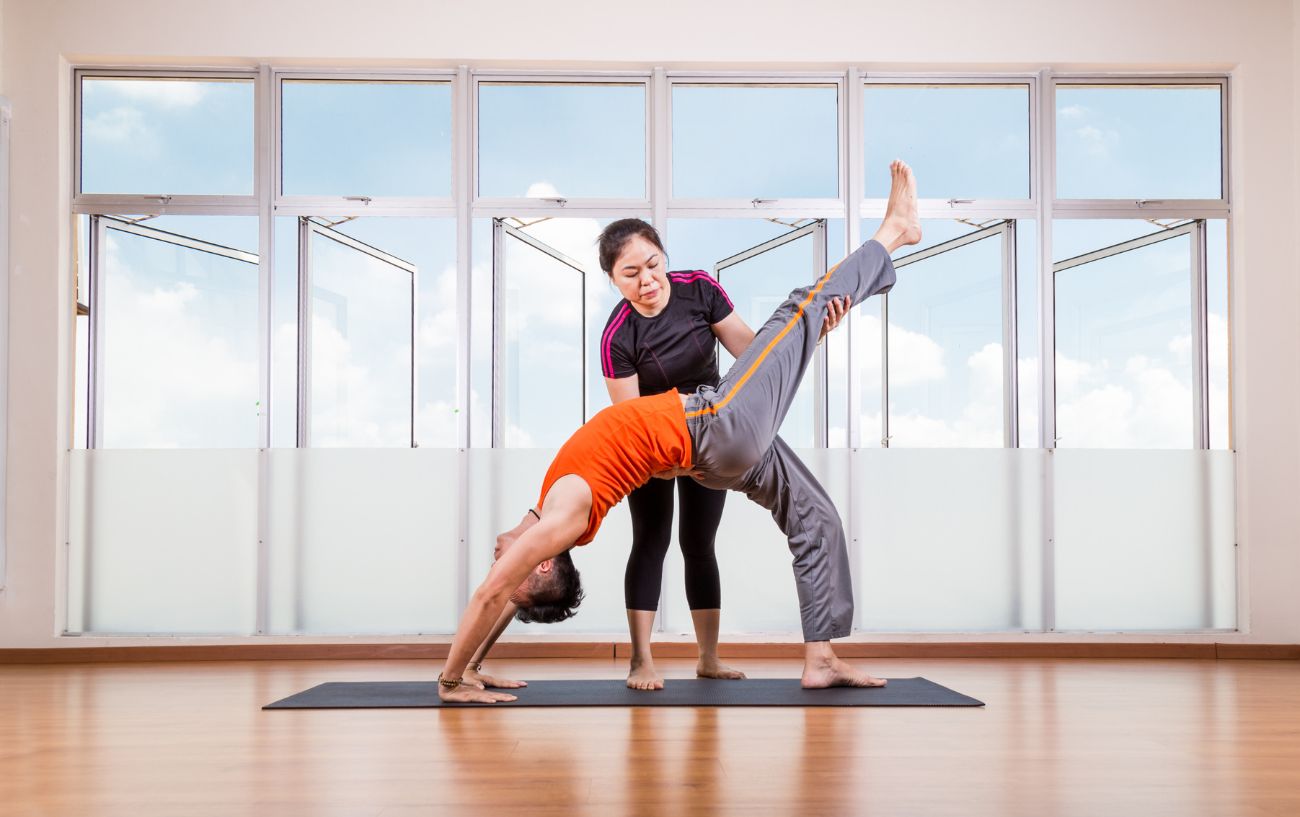 yoga teacher supporting student in a backbend