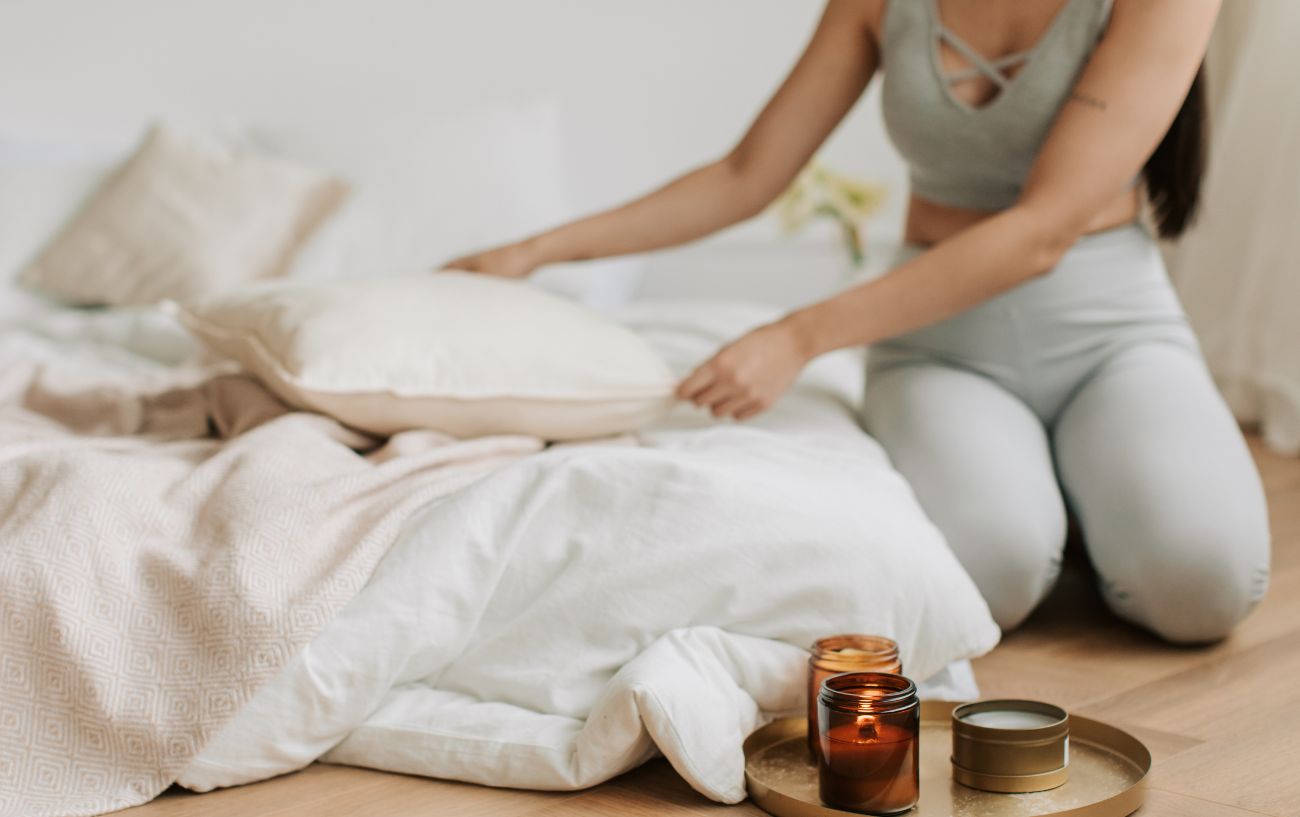 person making their bed with candles next to them