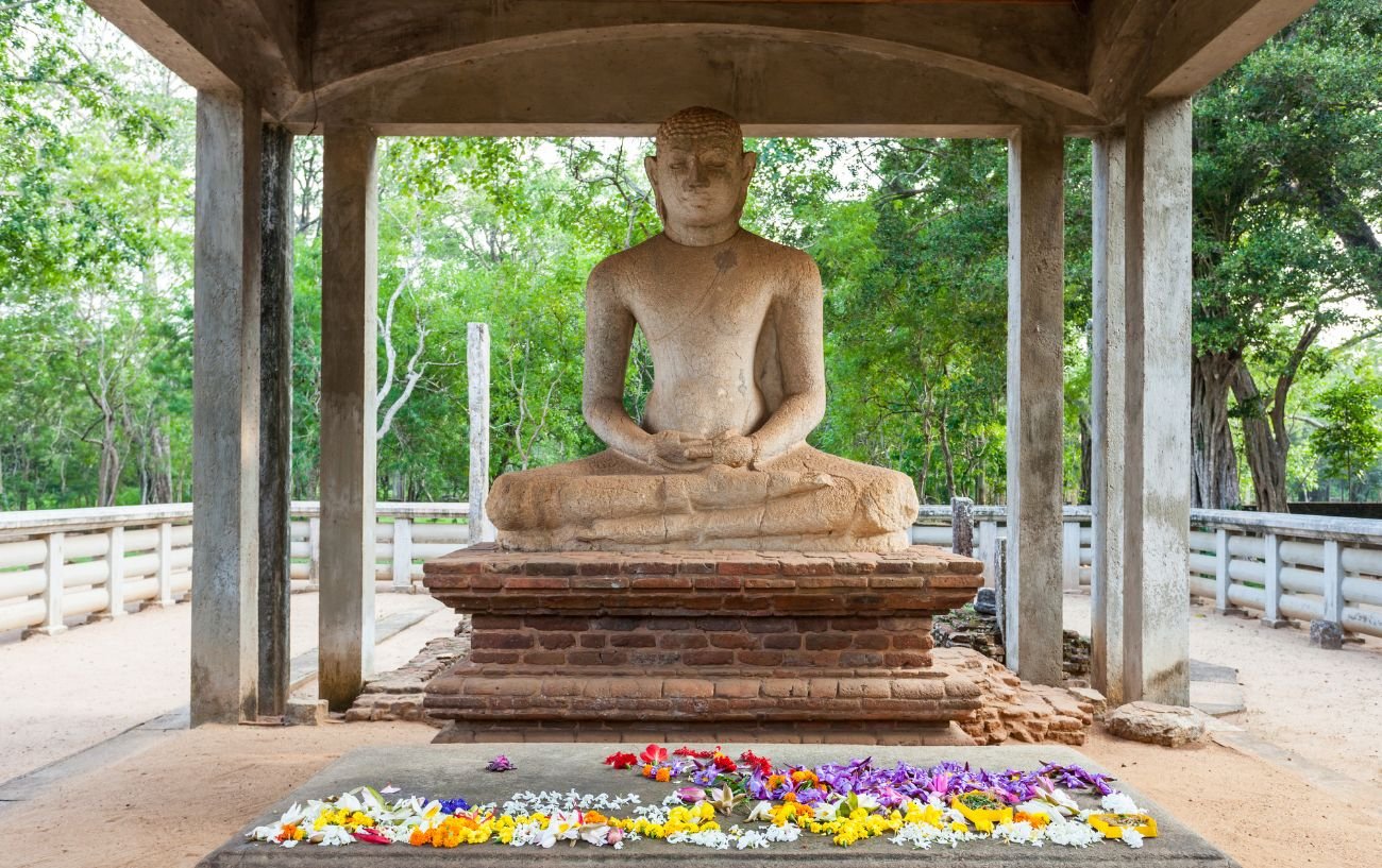 buddhist statue with flower offerings underneath