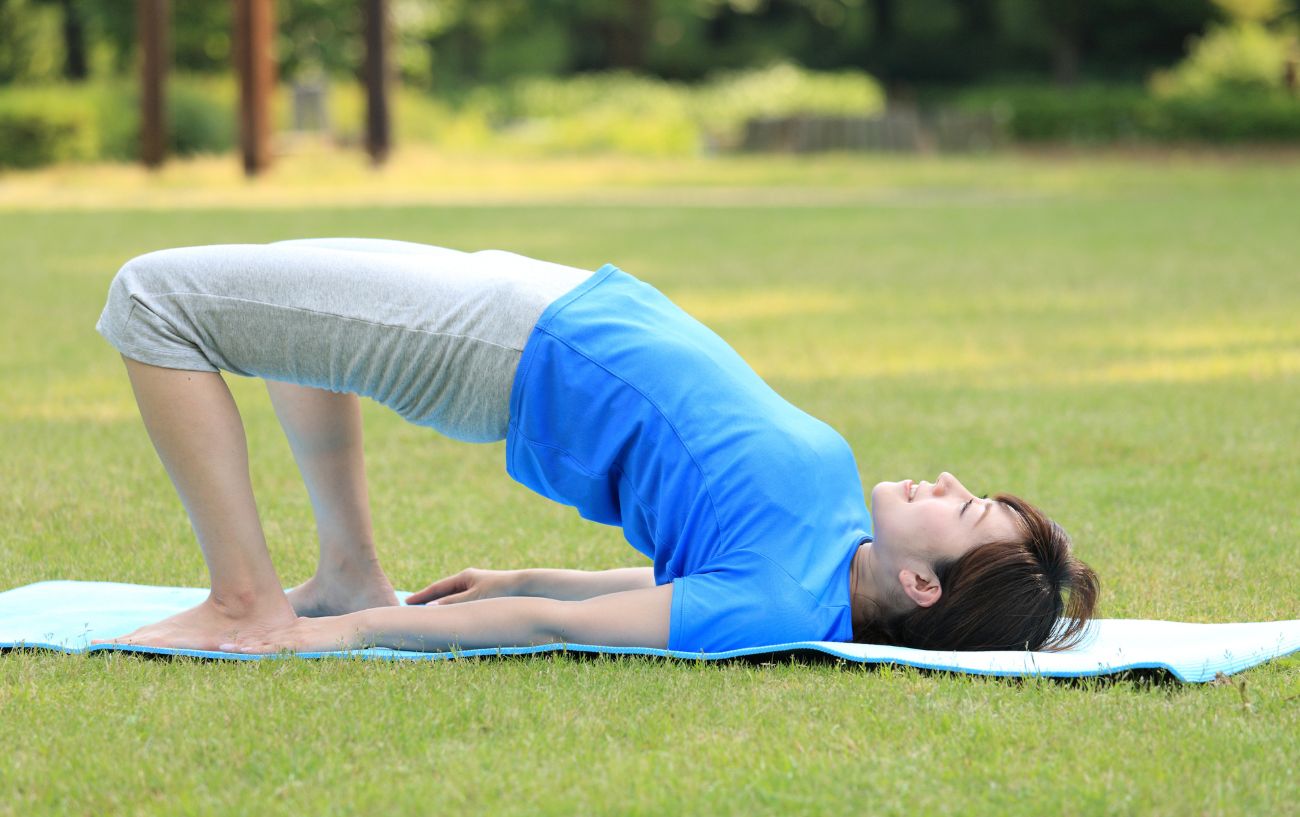 woman in bridge pose doing yoga outside