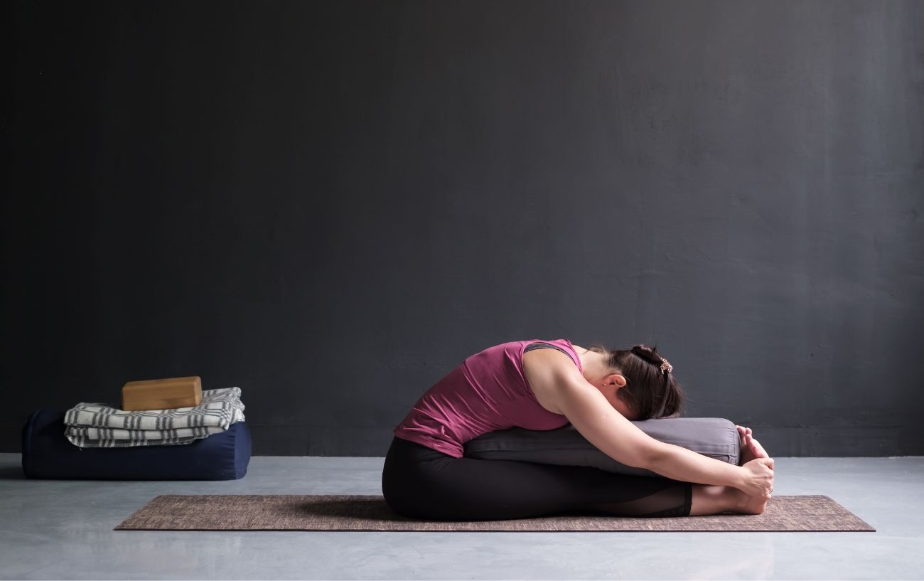 woman in supported forward fold using a bolster