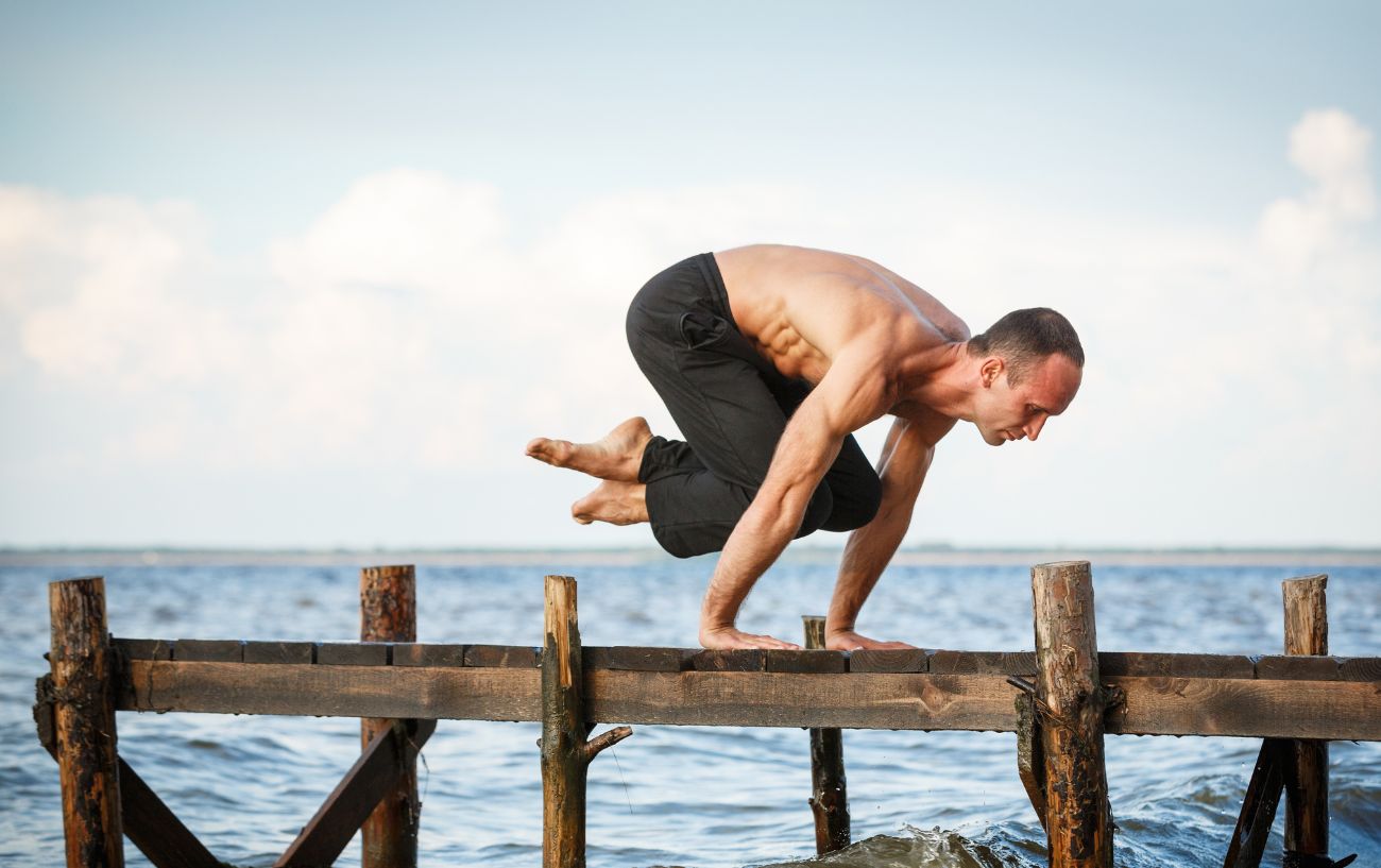 man doing lolasana by the sea