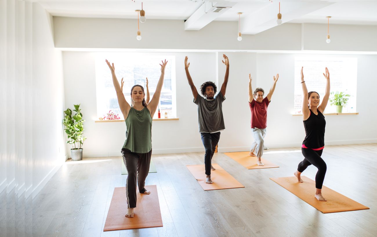 a group of yoga students doing warrior 1 pose in a yoga class