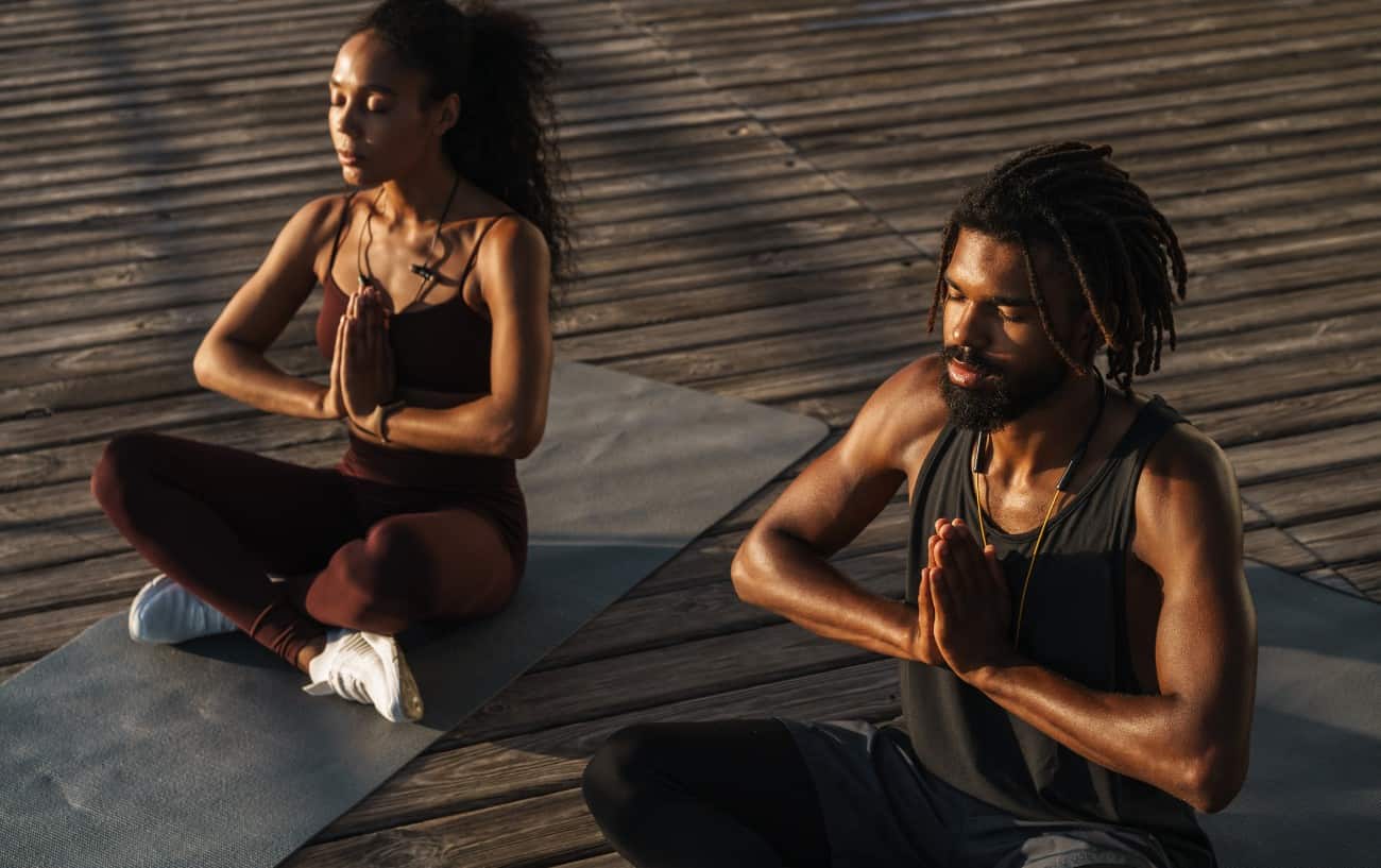 a man and a woman meditate together on some decking