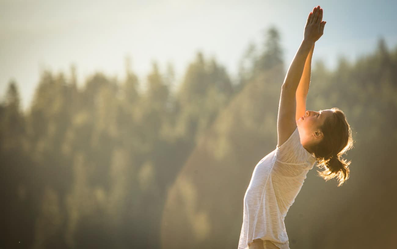 a woman practices yoga in nature