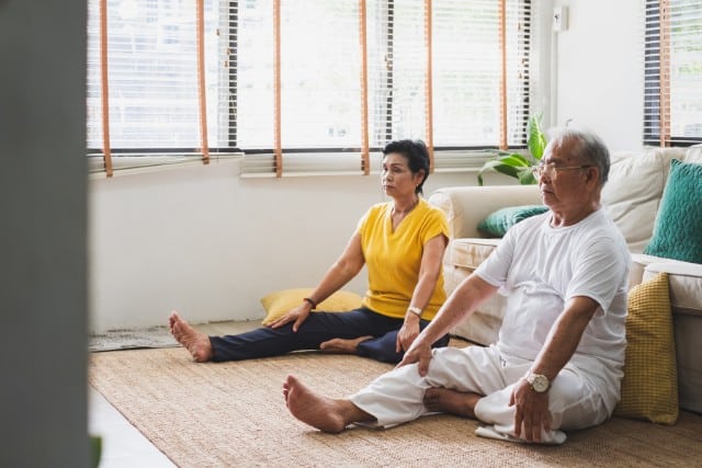 two older people doing yoga on the floor