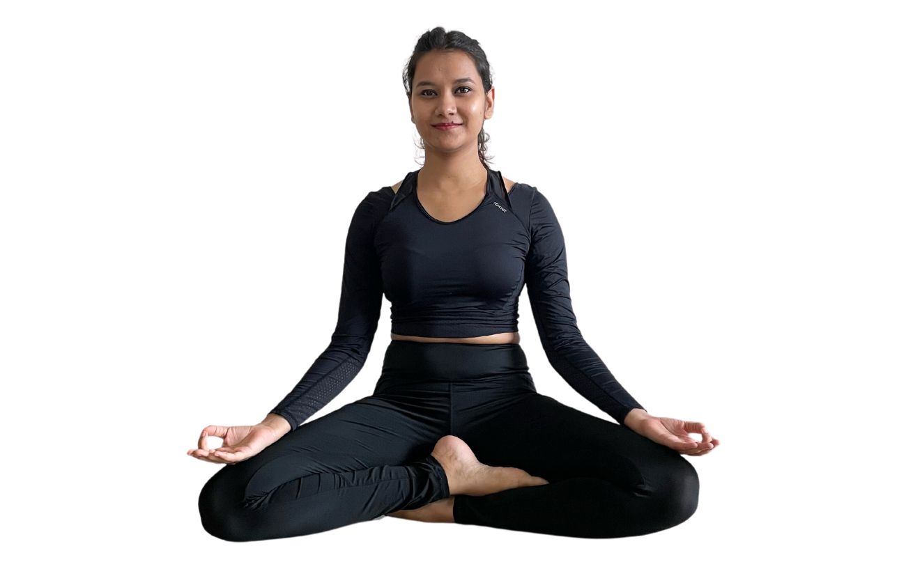 a woman in black yoga clothes sitting cross legged in accomplished posec