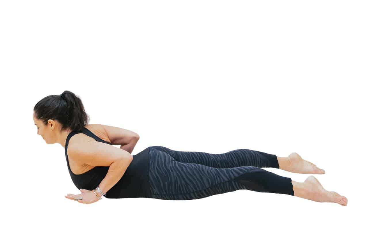 a woman wearing black yoga clothes doing a baby cobra variation with her hands hovering above the floor