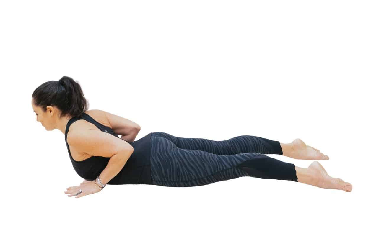 a picture of a woman wearing black yoga clothes doing a Baby Cobra pose