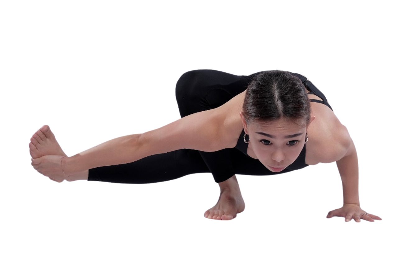 a woman wearing black yoga clothes doing baby grasshopper pose