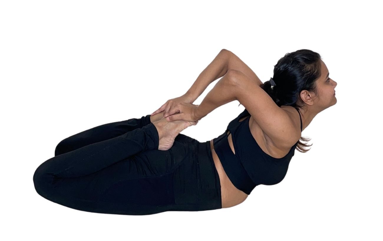 a woman in black yoga clothes doing bhekasana