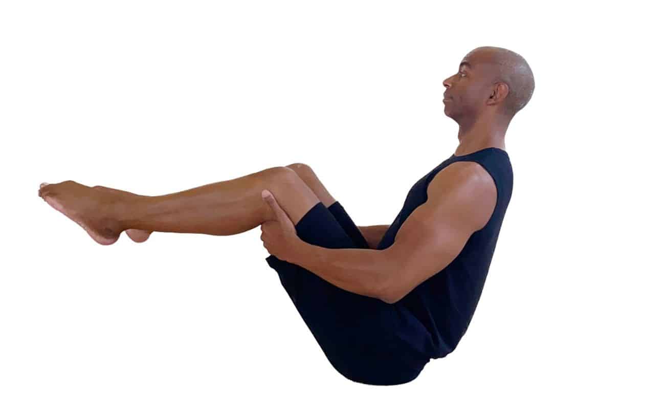 a man wearing all black doing plow pose with his knees bent