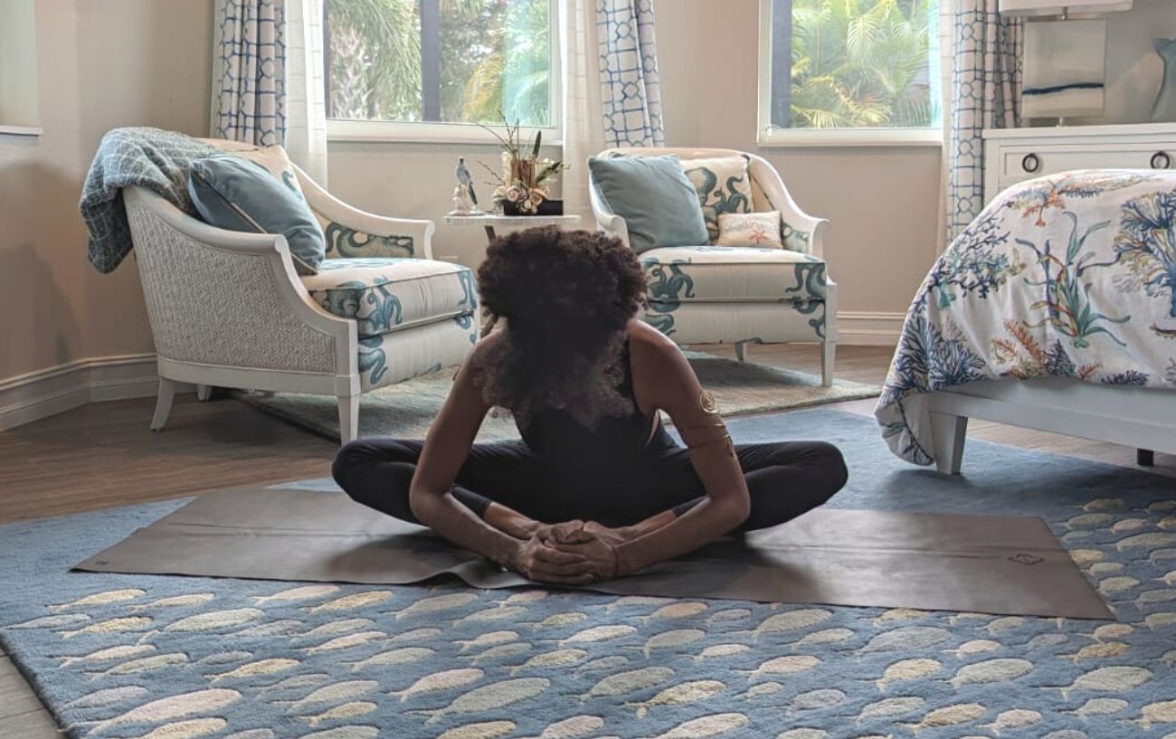 a woman doing bound angle pose in black yoga clothes in a living room