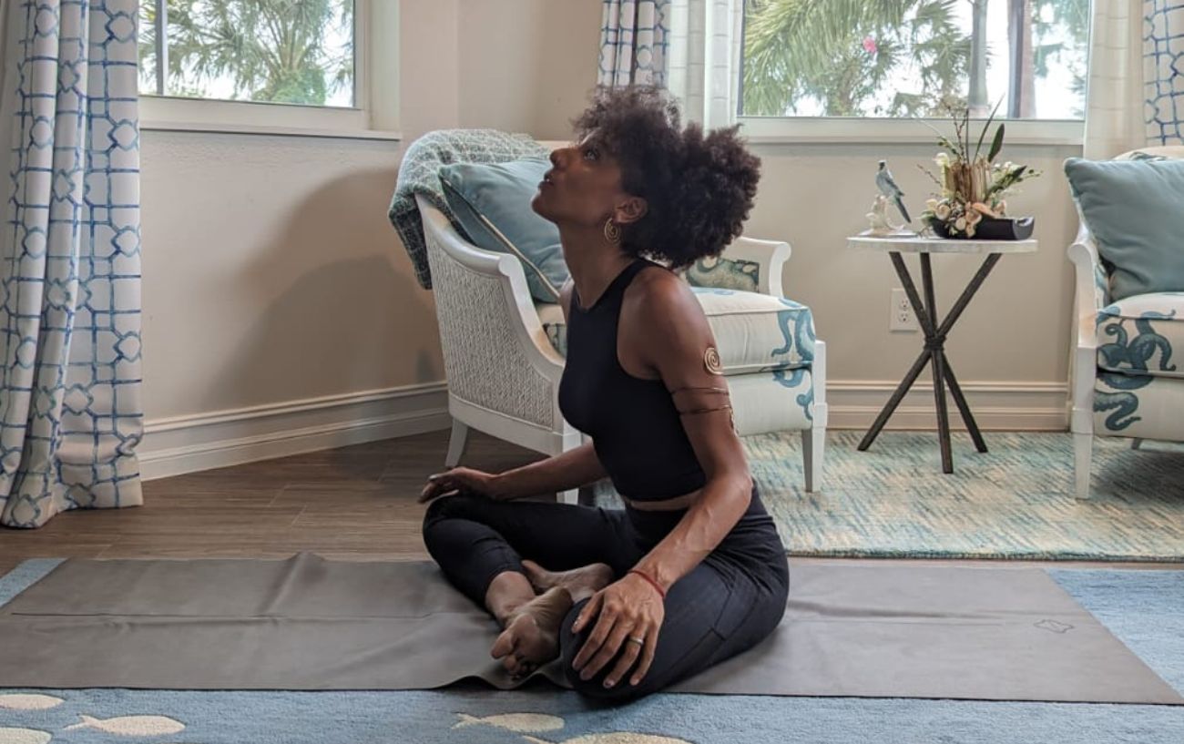 a woman wearing black yoga clothes doing yoga neck stretches cross legged in her living room