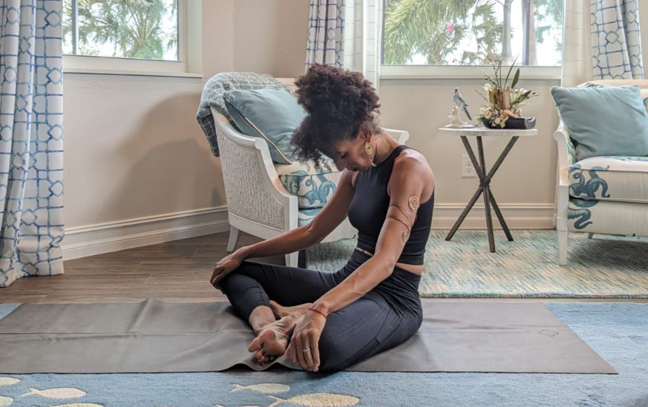 a woman wearing black yoga clothes doing yoga neck stretches cross legged in her living room