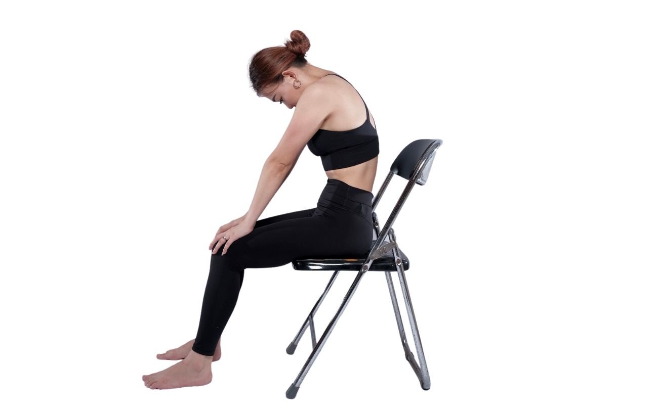 a woman wearing black yoga clothes doing cat pose on a chair