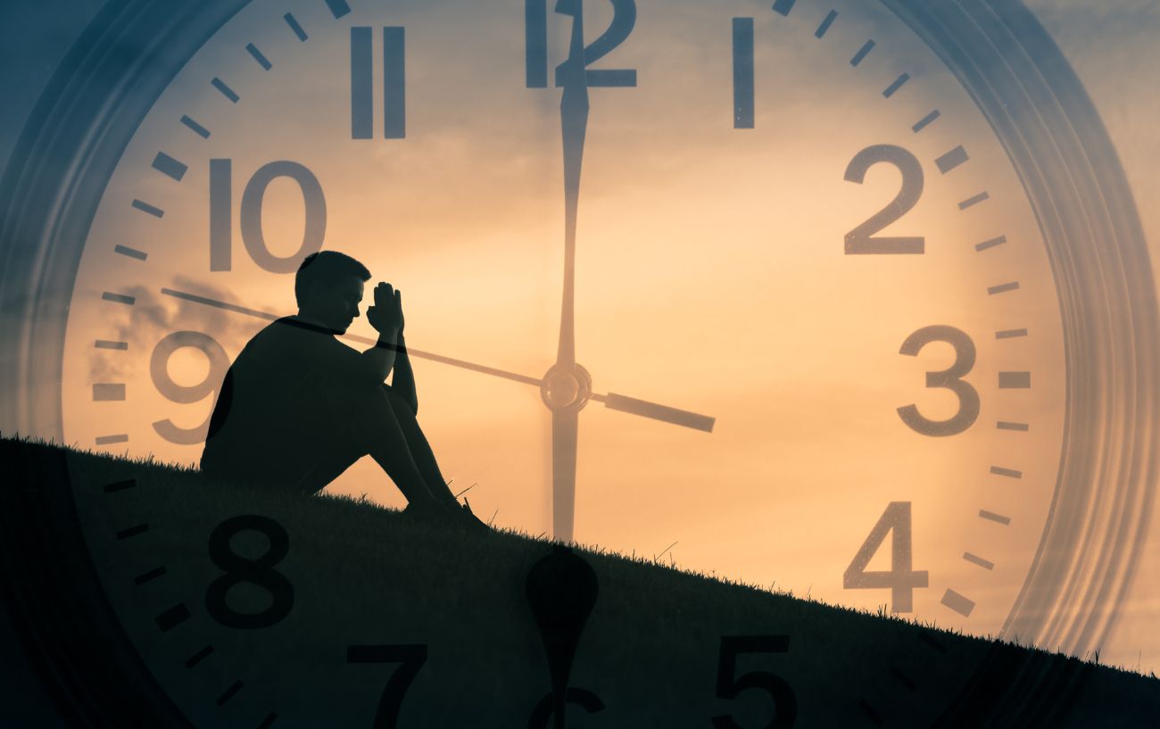 a man praying in front of a clock