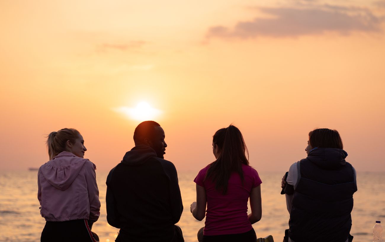 friends sitting in front of sunset