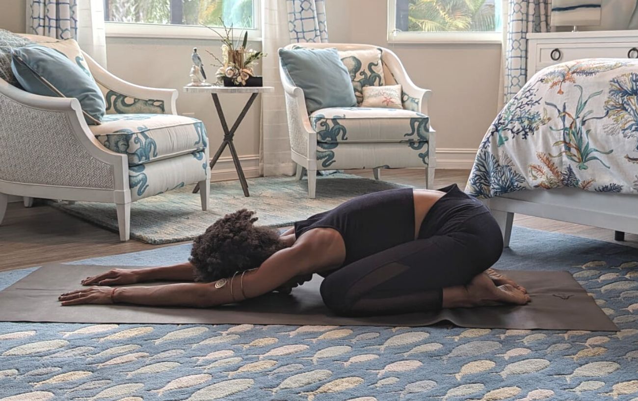 a woman doing child's pose in black yoga clothes in a living room