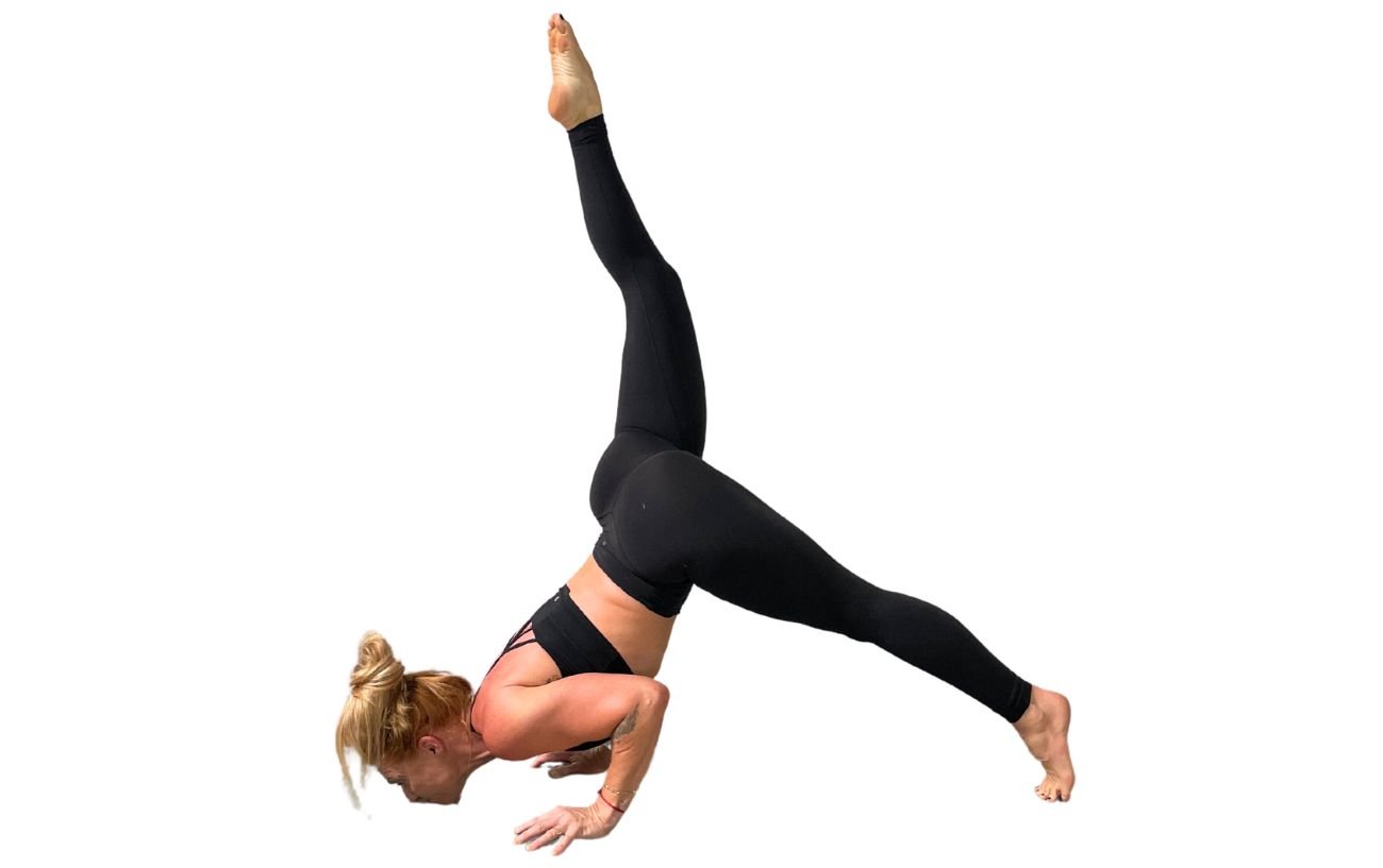 a woman wearing black yoga clothes doing chin stand pose with one leg down