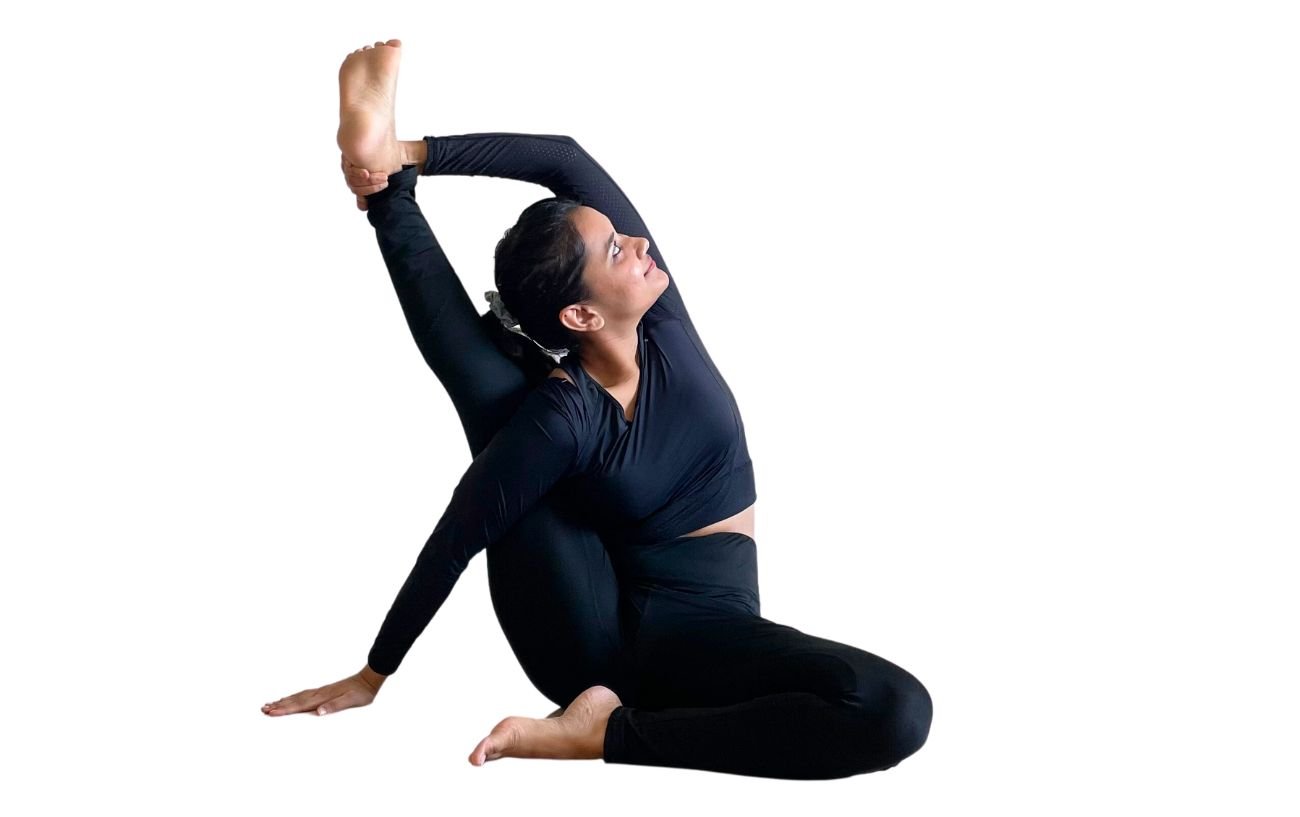 a woman wearing black yoga clothes doing compass pose