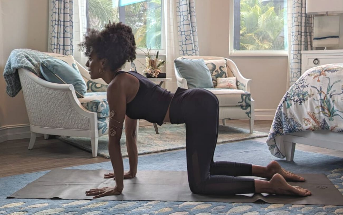 a woman doing cow pose in black yoga clothes in a living room