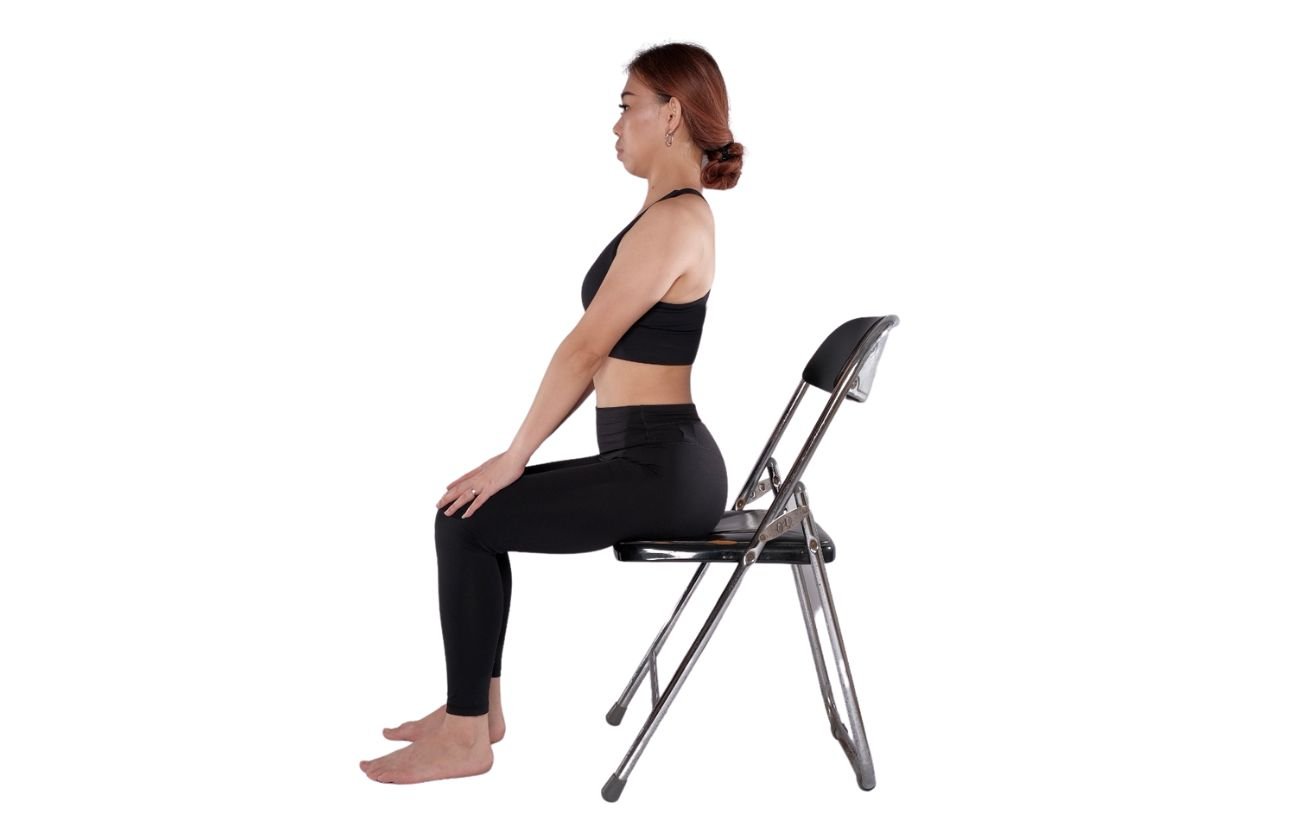 a woman wearing black yoga clothes doing cow pose on a chair