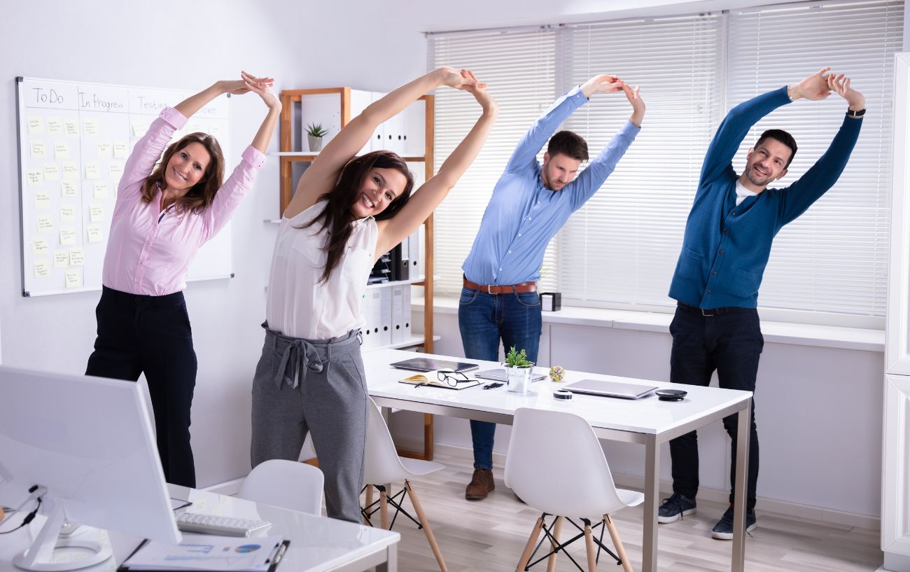 a group of office workers stretch at their desks