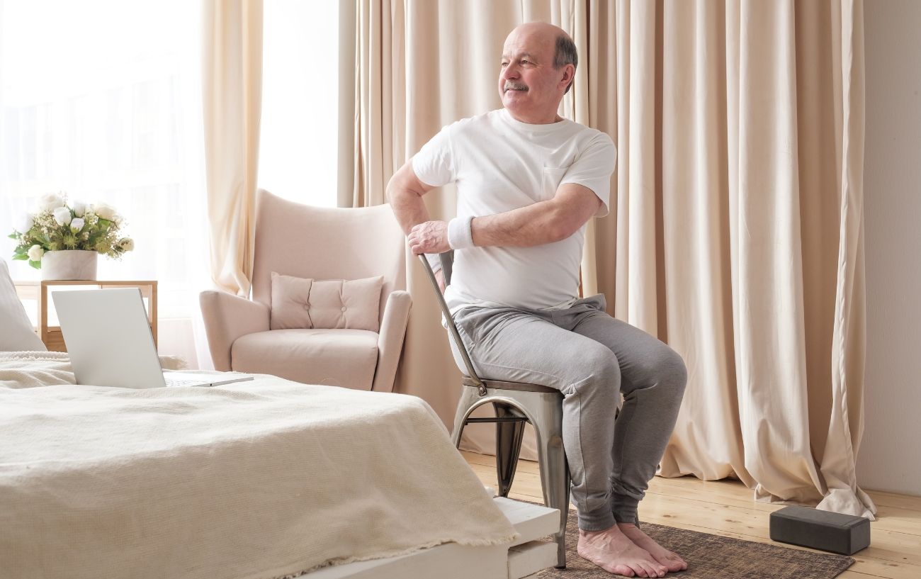 a man doing chair yoga in his bedroom