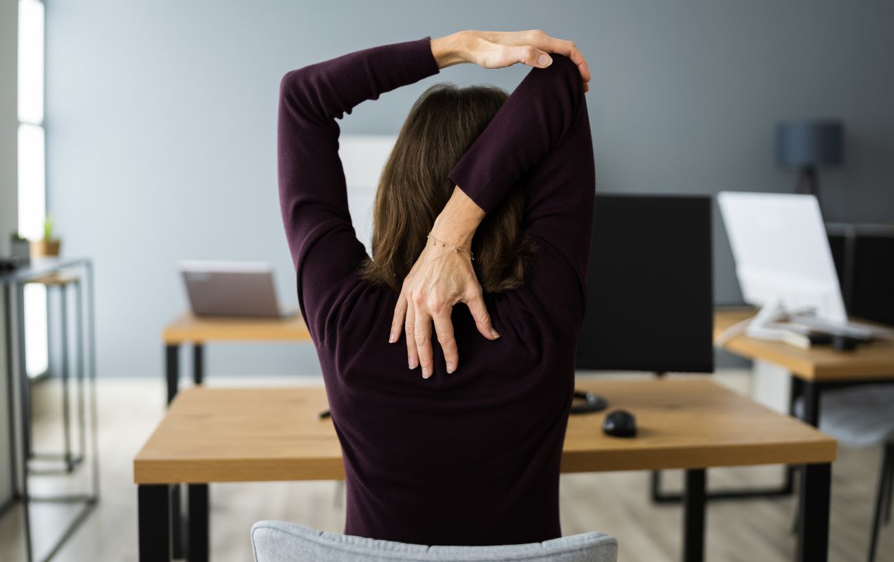 a woman stretches at her desk